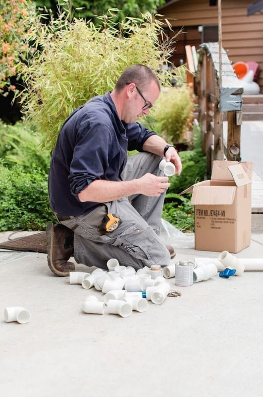 Plumber laying out PVC fittings on a driveway before a repipe