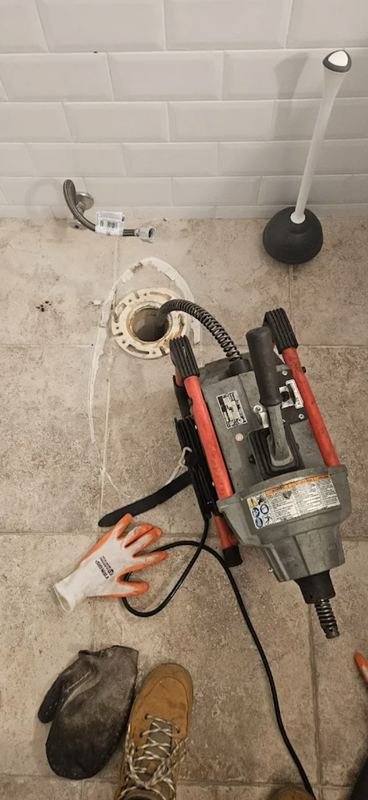 Toilet flange opening and a drain machine on a bathroom floor